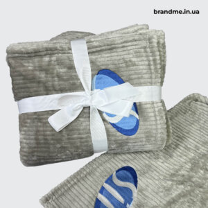 Мʼякий брендований плед із вишитим логотипом Сірий брендований плед із вишитим логотипом, перев'язаний білою стрічкою для подарункового оформлення