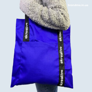 Яскравий шопер ekreative — зручність і впізнаваність у кожному русі Синя брендована сумка-шопер з написом на ручках