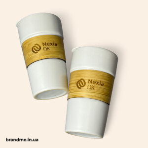 Дві багаторазові термочашки з логотипом Nexia DK — приклад екологічного брендованого посуду